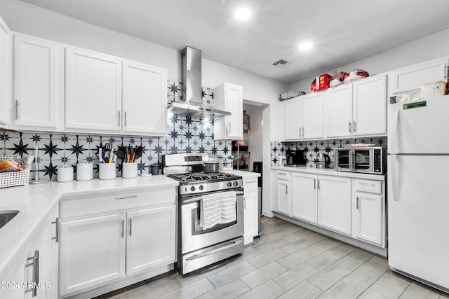 kitchen featuring white cabinetry, stainless steel appliances, and wall chimney range hood