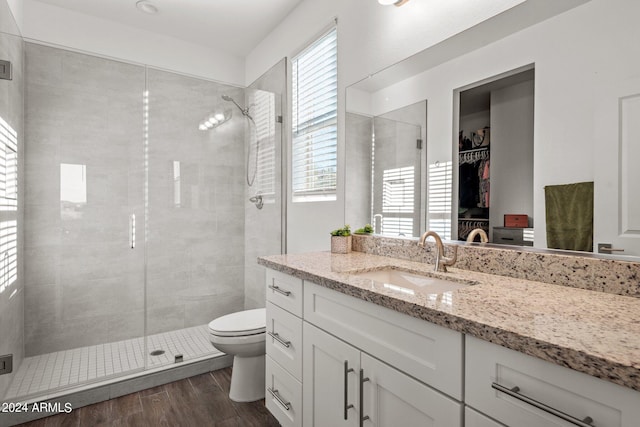 bathroom with a healthy amount of sunlight, wood-type flooring, walk in shower, and vanity