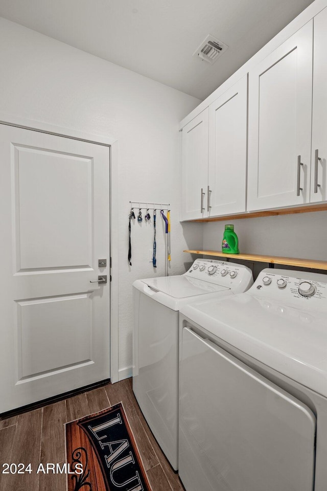 laundry area with cabinets, dark hardwood / wood-style floors, and washer and dryer