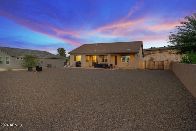 back house at dusk featuring a patio