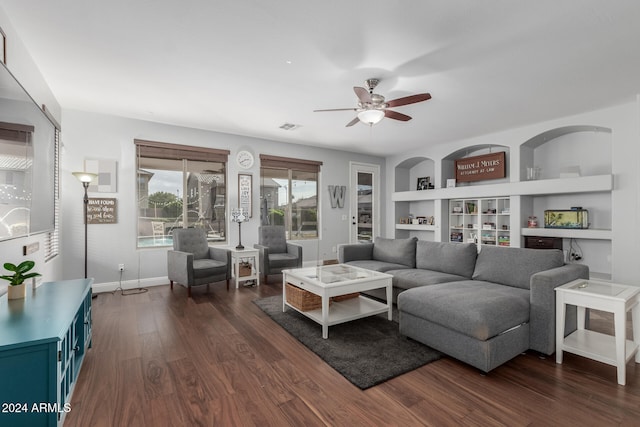 living room with built in features, dark hardwood / wood-style floors, and ceiling fan