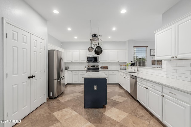 kitchen with light stone counters, sink, a kitchen island, white cabinetry, and stainless steel appliances