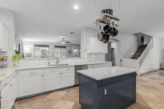 kitchen featuring stainless steel dishwasher, sink, kitchen peninsula, white cabinetry, and backsplash