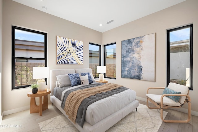 bedroom featuring light wood-style flooring, visible vents, and baseboards