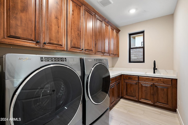 washroom with cabinet space, washing machine and dryer, visible vents, and a sink