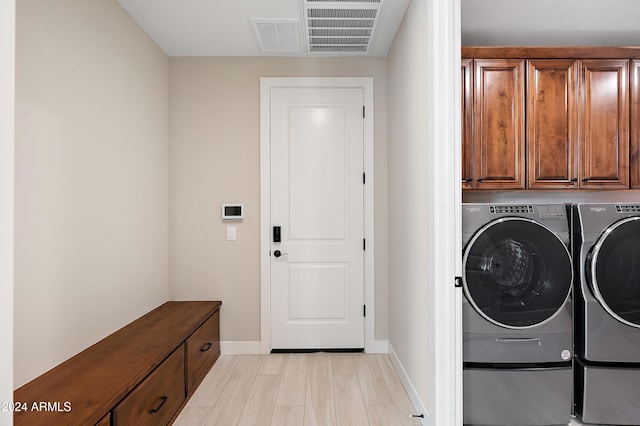 laundry area featuring visible vents, cabinet space, washer and clothes dryer, and baseboards