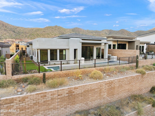 rear view of property with a fenced backyard, a mountain view, and stucco siding