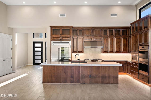 kitchen featuring a towering ceiling, under cabinet range hood, visible vents, and appliances with stainless steel finishes