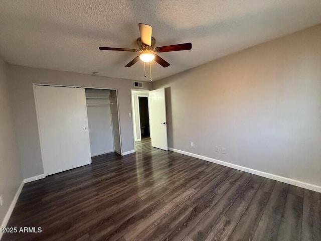 unfurnished bedroom featuring dark wood finished floors, baseboards, visible vents, and a closet