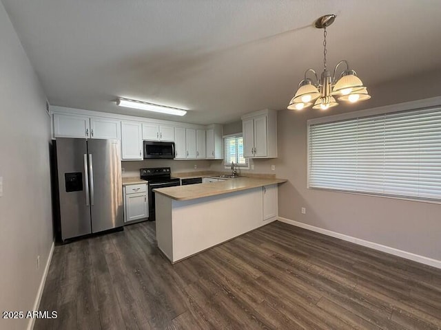 kitchen featuring dark wood-style floors, a peninsula, a sink, light countertops, and appliances with stainless steel finishes