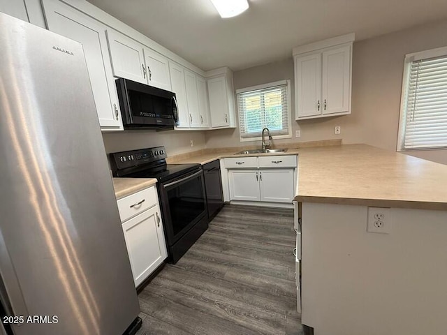 kitchen with freestanding refrigerator, black / electric stove, a peninsula, light countertops, and dishwasher