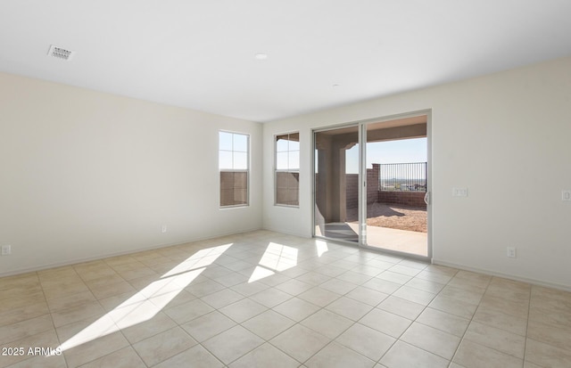 empty room featuring light tile patterned flooring, visible vents, and baseboards