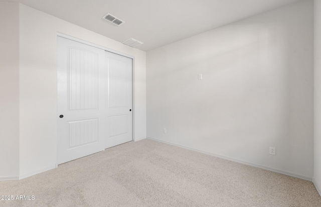 unfurnished bedroom featuring a closet, visible vents, light carpet, and baseboards