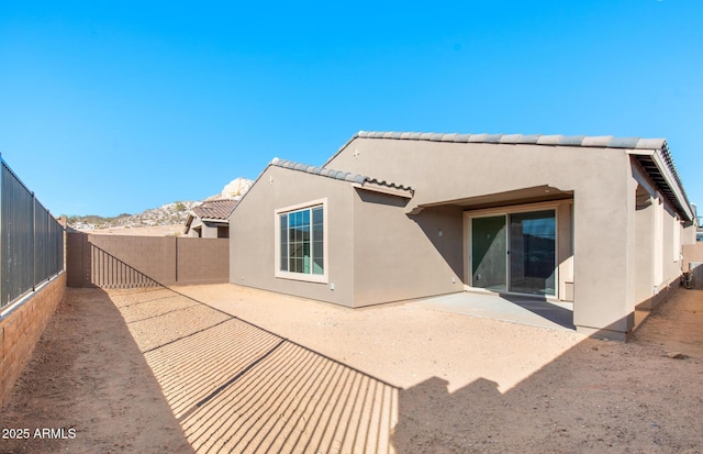 rear view of house featuring a patio, a fenced backyard, a tiled roof, and stucco siding