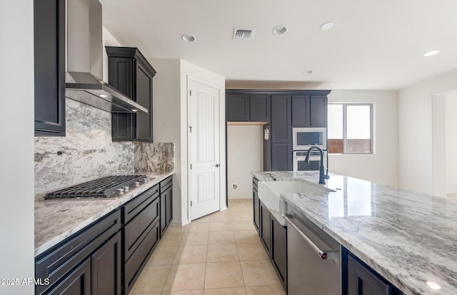 kitchen with stainless steel appliances, visible vents, wall chimney range hood, and light stone countertops