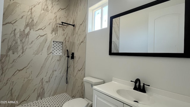 bathroom featuring toilet, a marble finish shower, and vanity