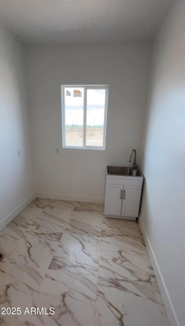 interior space with baseboards, marble finish floor, and a sink