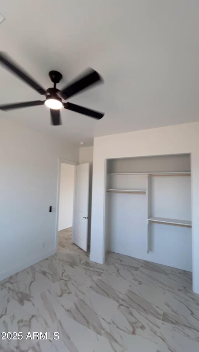 unfurnished bedroom featuring ceiling fan, marble finish floor, and a closet