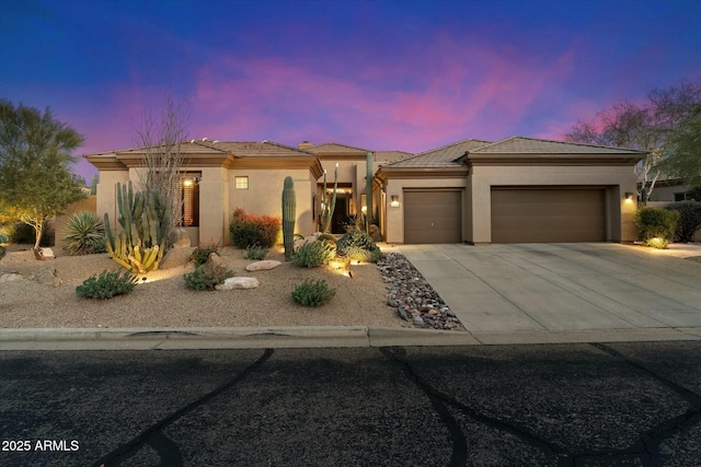 prairie-style home featuring an attached garage, a tiled roof, concrete driveway, and stucco siding