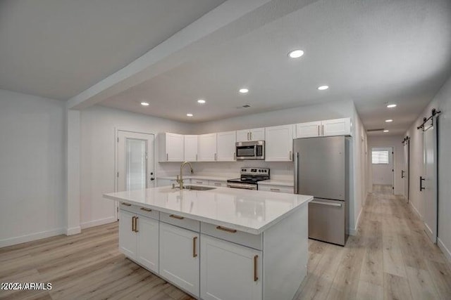 kitchen featuring sink, stainless steel appliances, a barn door, and white cabinets