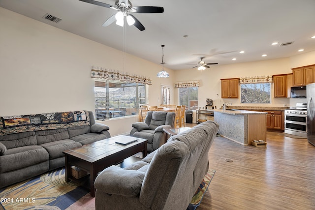 living room featuring ceiling fan, sink, and dark hardwood / wood-style floors