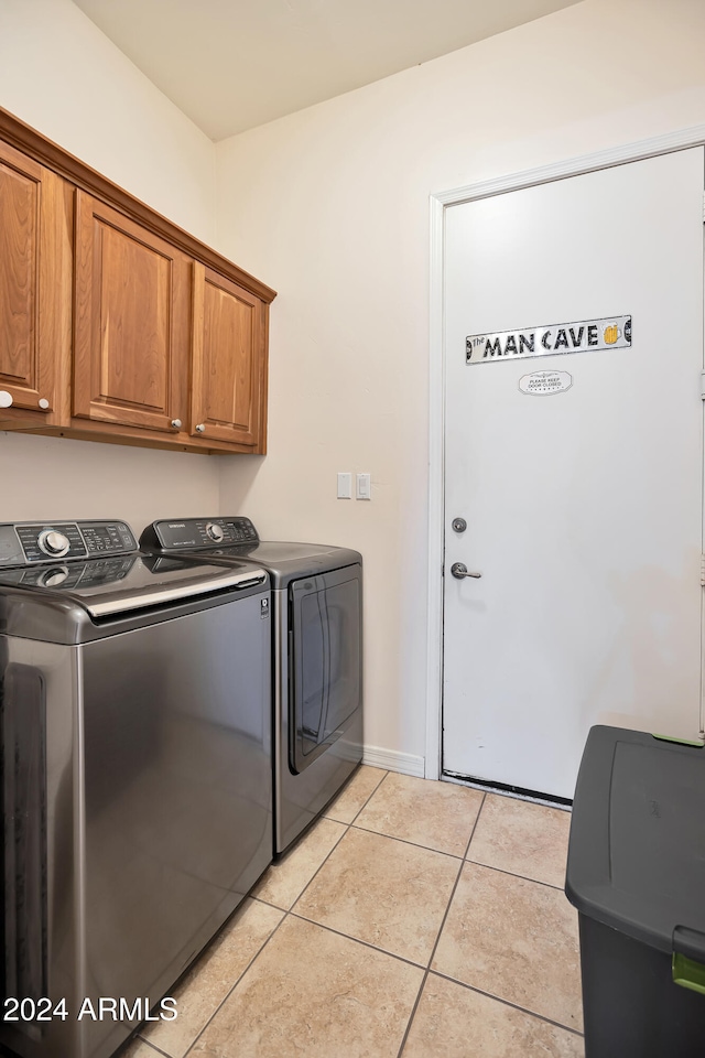 laundry area featuring cabinets, light tile patterned flooring, and washer and dryer