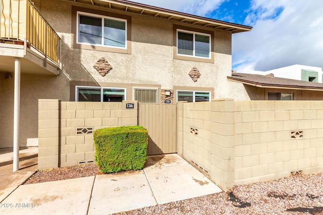 view of front of home featuring a balcony, a fenced front yard, and stucco siding