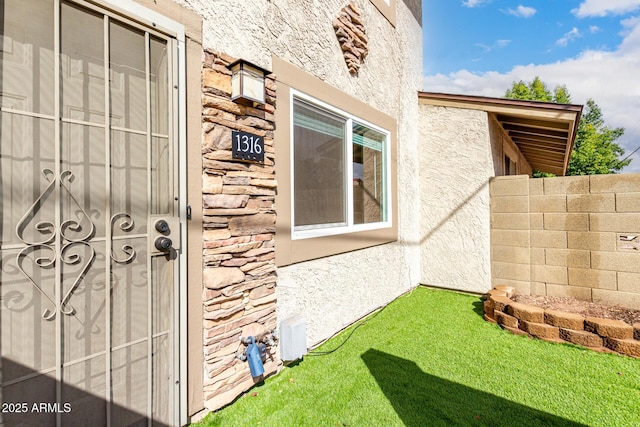 view of exterior entry featuring stone siding and stucco siding