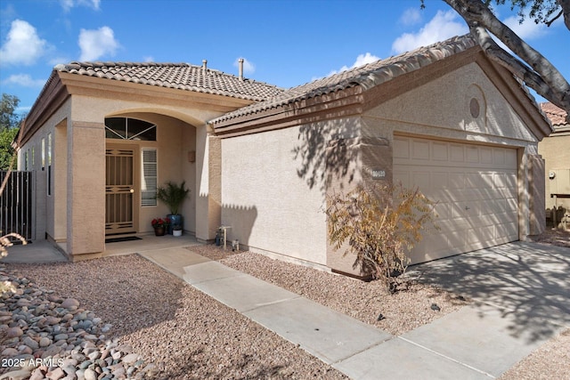 view of front of home with a garage, driveway, a tiled roof, and stucco siding