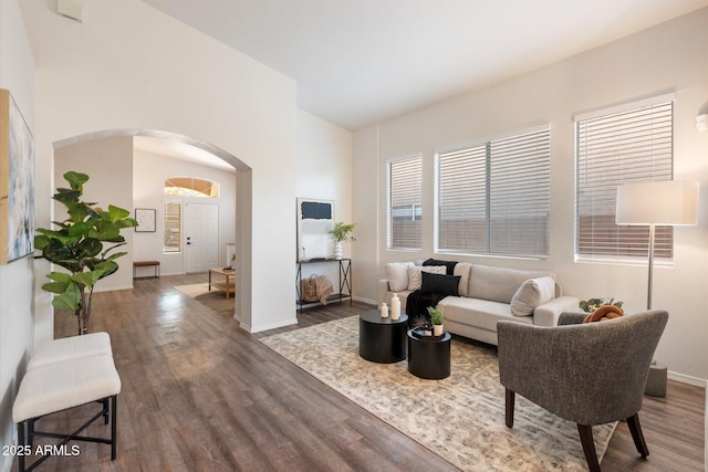 interior space with arched walkways, dark wood finished floors, and a healthy amount of sunlight