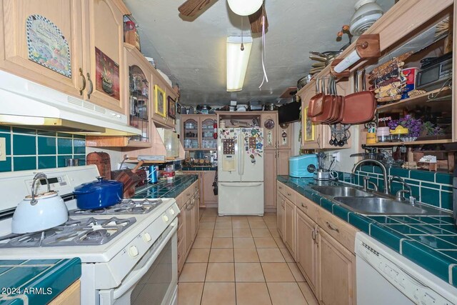 kitchen with tile counters, sink, white appliances, light tile patterned floors, and ceiling fan