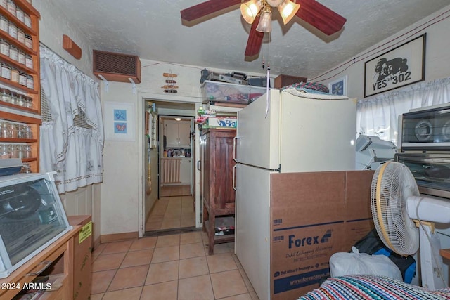 interior space featuring ceiling fan, light tile patterned flooring, and a textured ceiling