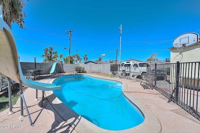 view of pool with a water slide and a patio area