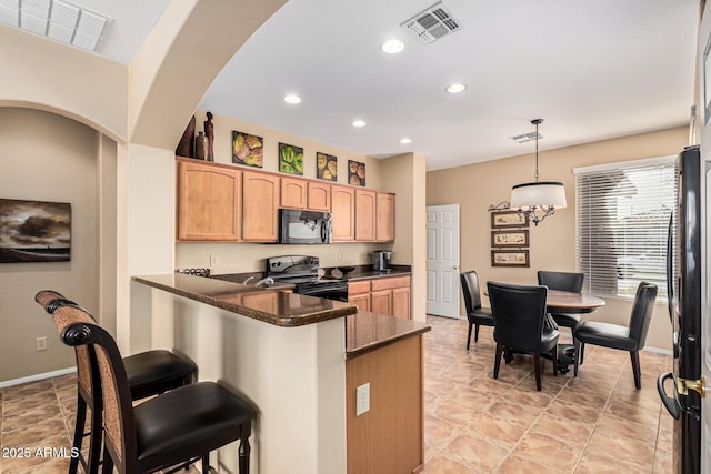 kitchen with a kitchen bar, kitchen peninsula, pendant lighting, dark stone counters, and black appliances