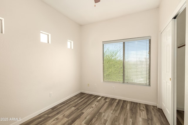 unfurnished bedroom featuring dark wood finished floors, baseboards, a closet, and a ceiling fan