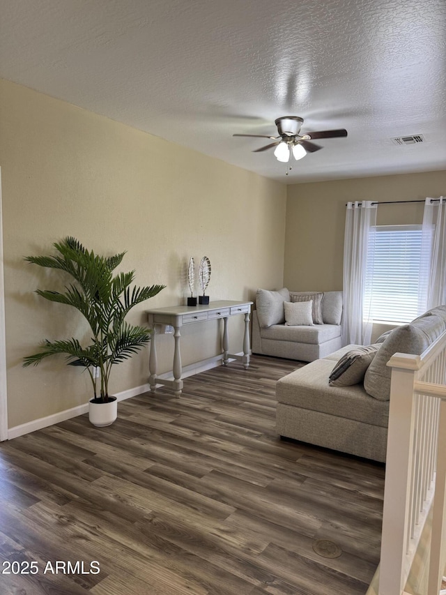 living area featuring wood finished floors, a ceiling fan, baseboards, and a textured ceiling