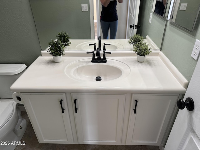 bathroom with vanity, toilet, and a textured wall