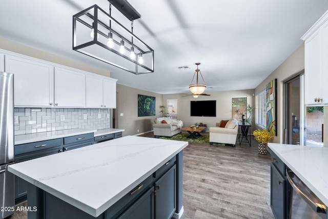 kitchen featuring tasteful backsplash, visible vents, white cabinets, open floor plan, and hanging light fixtures