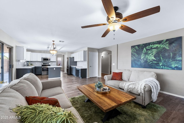 living area featuring arched walkways, visible vents, baseboards, and wood finished floors