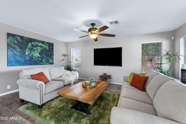 living room with visible vents, wood finished floors, a ceiling fan, and baseboards