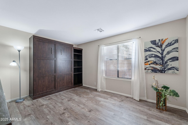 unfurnished bedroom featuring baseboards, visible vents, and light wood finished floors