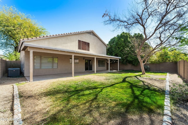 back of house with a fenced backyard, a lawn, a patio, and stucco siding