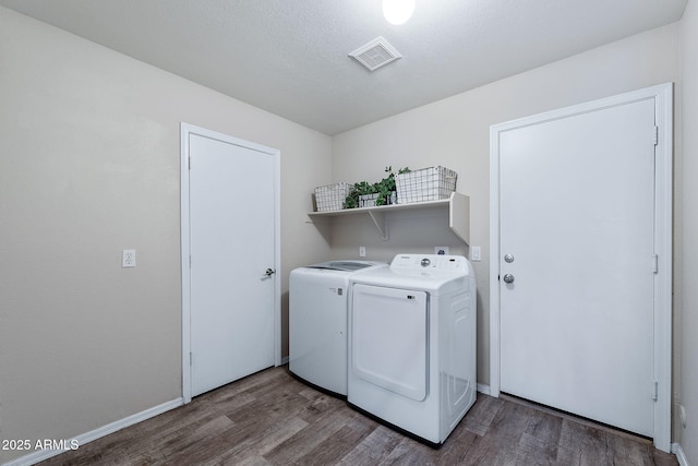 washroom featuring laundry area, baseboards, visible vents, wood finished floors, and independent washer and dryer