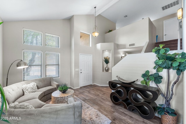 living area with high vaulted ceiling, beamed ceiling, wood finished floors, and visible vents