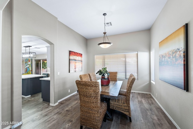 dining room featuring arched walkways, dark wood-style flooring, visible vents, and baseboards