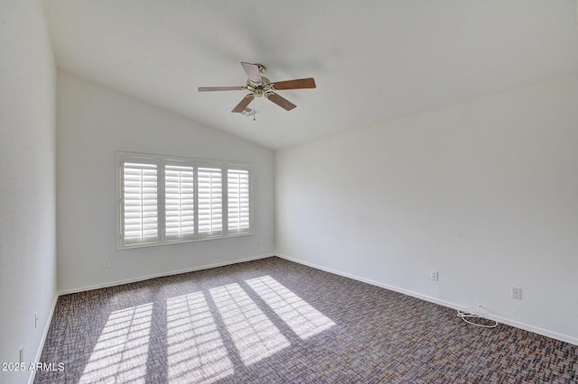 spare room featuring ceiling fan, vaulted ceiling, and dark colored carpet