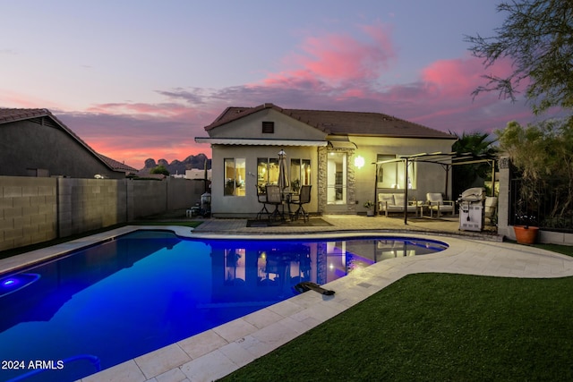 pool at dusk with a pergola and a patio