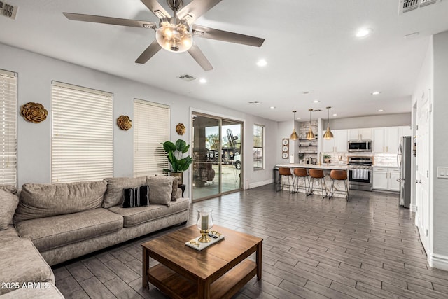 living room featuring ceiling fan and dark hardwood / wood-style flooring