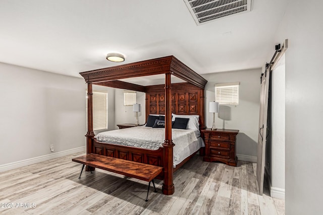 bedroom with a barn door and light hardwood / wood-style floors