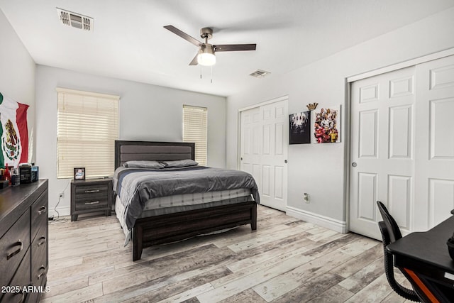 bedroom featuring ceiling fan, light hardwood / wood-style floors, and two closets